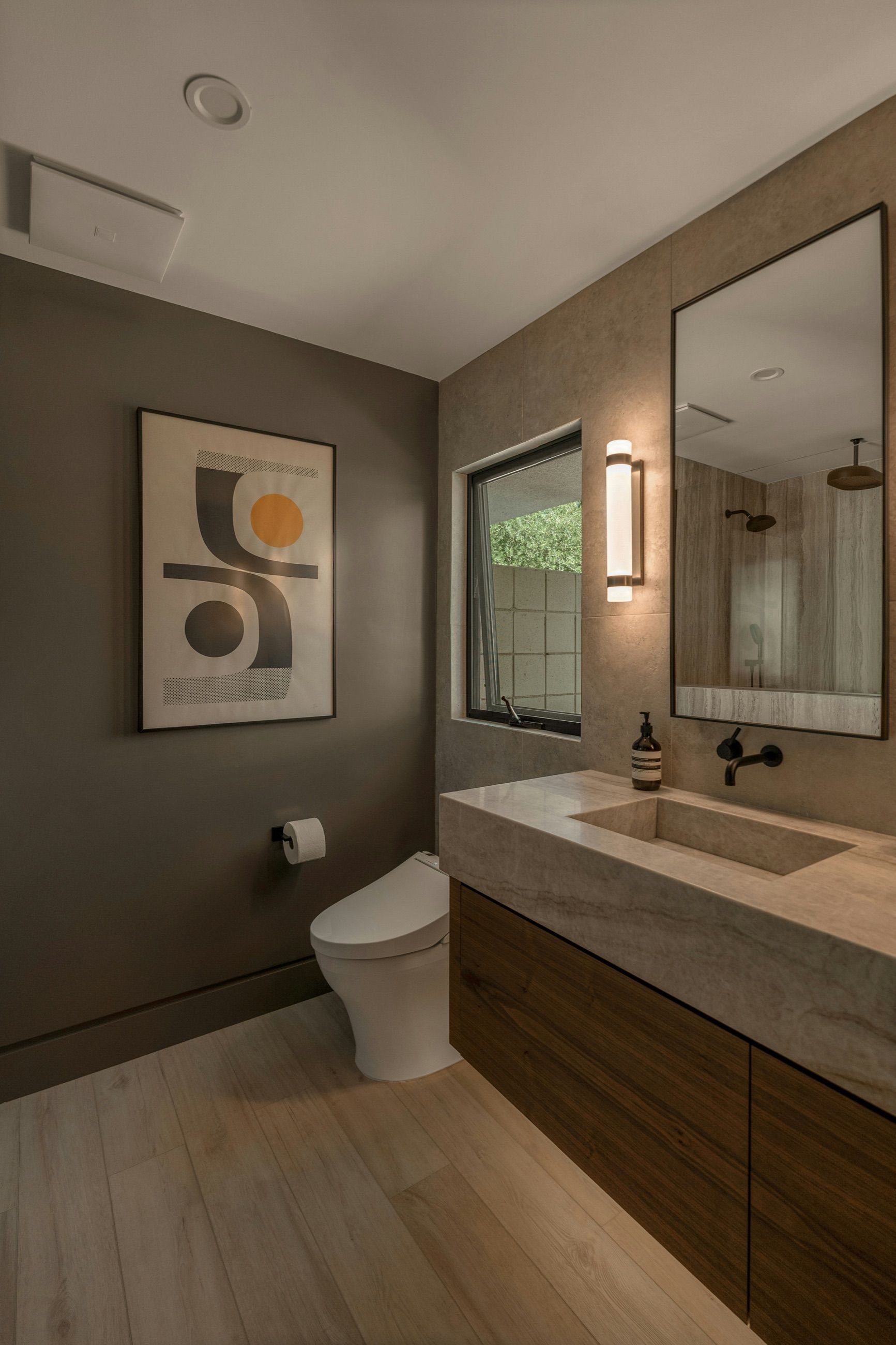 A bathroom we remodeled: stone vanity, walnut cabinet and a wall-mounted faucet.